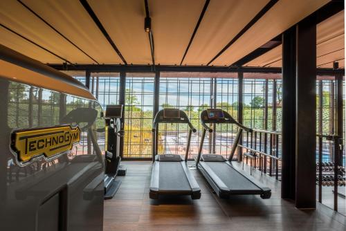 a gym with treadmills in a building with windows at Villaverde Hotel Spa&Golf Udine in Fagagna