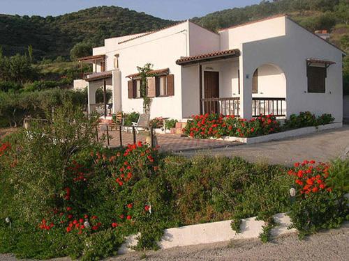 a white house with flowers in front of it at Limenaria Apartments in Mochlos