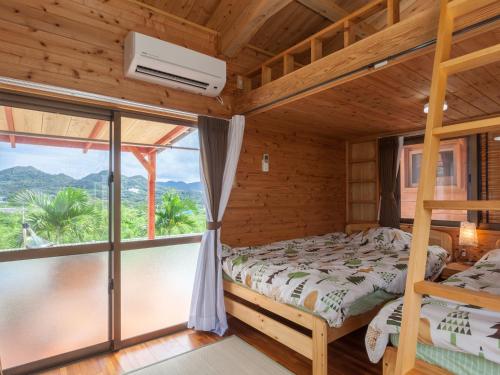 a bedroom with a bed and a large window at もとぶいこいの宿 やまちゃん in Motobu