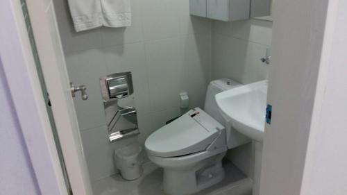 a white bathroom with a toilet and a sink at Gaon Residence Hotel in Daejeon