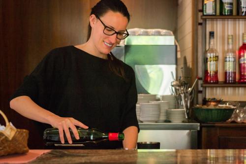 a woman standing in a kitchen pouring a bottle of wine at Hotel Comtes De Challant Albergo Etico Valle d'Aosta in Fenis