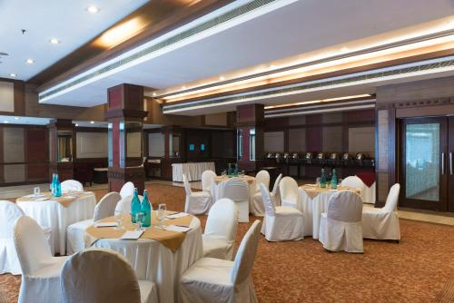 a banquet hall with white tables and white chairs at Park Inn by Radisson,South Delhi in New Delhi