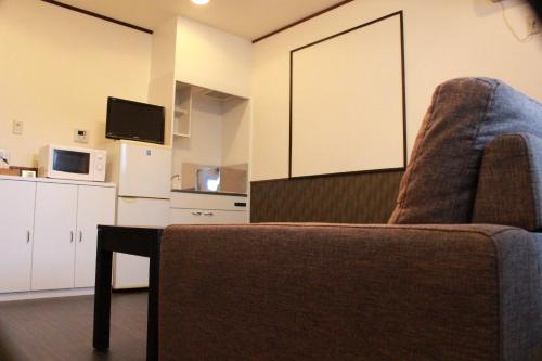 a living room with a couch and a microwave at Nangoku Lodge Booya in Onna