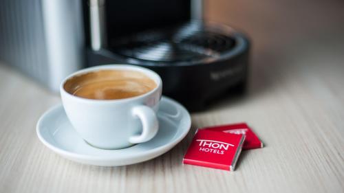 a cup of coffee on a plate next to a microwave at Thon Hotel Nordlys in Bodø