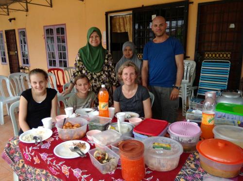 a group of people standing around a table with food at My Friend Homestay in Kota Bharu
