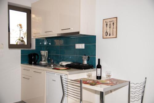kuchnia z białymi szafkami i stołem z butelką wina w obiekcie Efrilias Studios & Apartments w mieście Kisamos