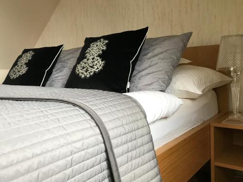 Una cama con almohadas blancas y negras. en Vila Mia Valtice en Valtice