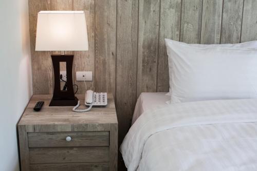 a bedroom with a bed with a lamp and a phone at Anchan Laguna Hotel โรงแรมอัญชันลากูน่า in Khon Kaen