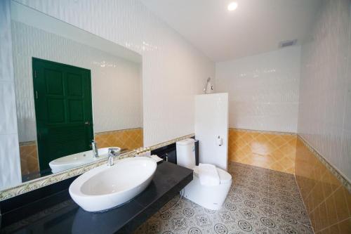 a bathroom with a sink and a toilet and a green door at Anchan Laguna Hotel โรงแรมอัญชันลากูน่า in Khon Kaen
