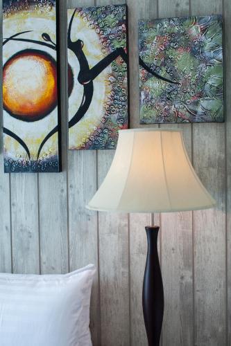 a lamp in a bedroom with paintings on the wall at Anchan Laguna Hotel โรงแรมอัญชันลากูน่า in Khon Kaen