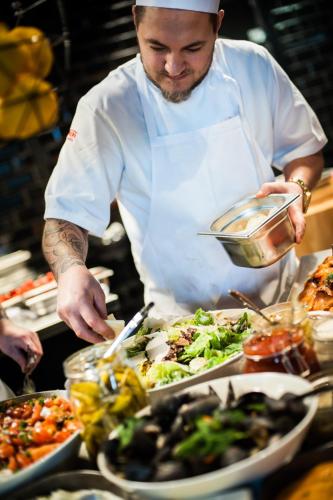 a man preparing food in a kitchen with plates of food at Thon Hotel Nordlys in Bodø