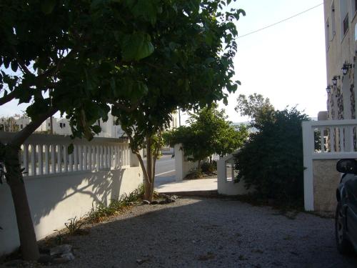 a white fence and a tree in front of a house at Margarita in Perissa