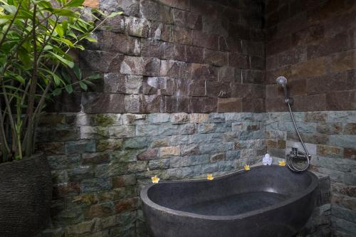 a bath tub in a room with a brick wall at Virmas Private Villa in Ubud