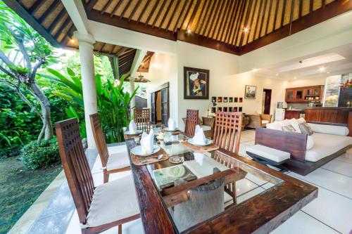 a dining room and living room with a table and chairs at Villa Frangipani in Sanur