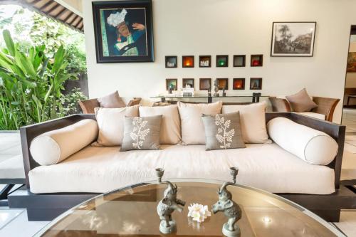 a living room with a white couch and a glass table at Villa Frangipani in Sanur