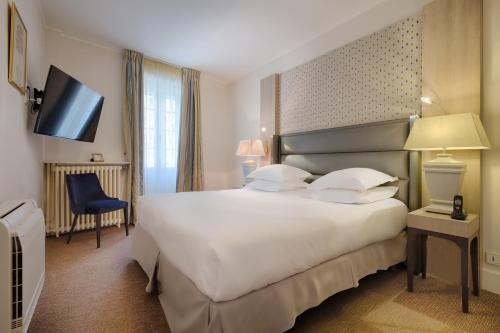 a hotel room with a large bed and a television at Auberge du Bon Laboureur Chenonceaux in Chenonceaux