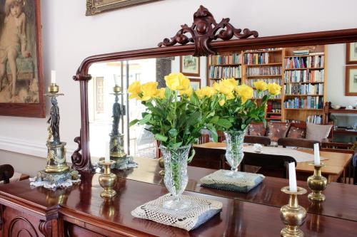 a table with two vases with yellow flowers on it at AmaSun B&B in George