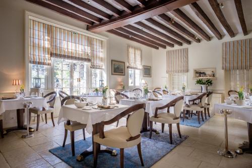 a restaurant with white tables and chairs and windows at Auberge du Bon Laboureur Chenonceaux in Chenonceaux