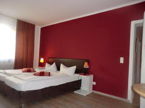 a bedroom with a large bed with a red wall at Hotel Pension Haydn in Munich