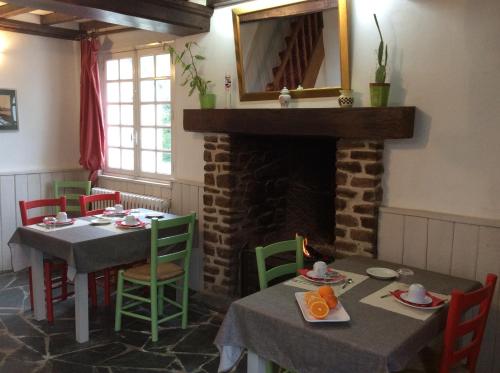 une salle à manger avec deux tables et une cheminée dans l'établissement La Verte Campagne - 50660 Trelly, à Trelly