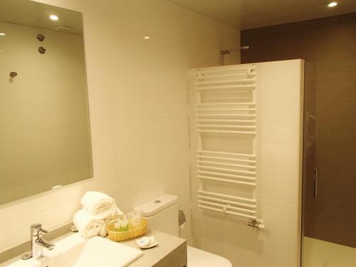 Un baño con lavabo y ducha con espejo. en Apartamentos Voramar, en Castelldefels