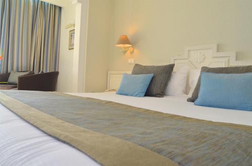 a bedroom with a large bed with blue pillows at Royal Garden Palace - Families and Couples in Midoun
