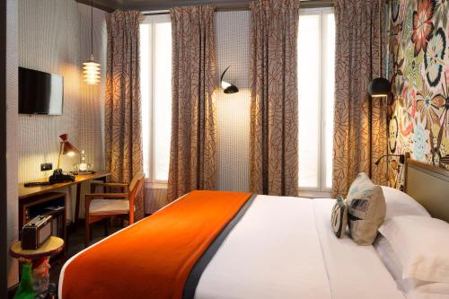 a hotel room with a bed and a desk and windows at Hôtel Les Dames du Panthéon in Paris