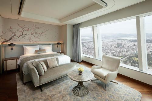 a bedroom with a bed and a couch and a chair at Signiel Seoul in Seoul