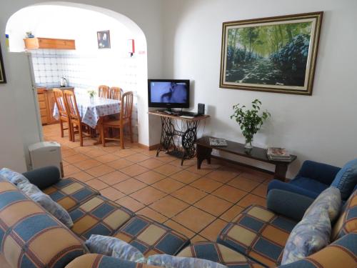 a living room with couches and a table and a tv at Casa Formosa in Furnas