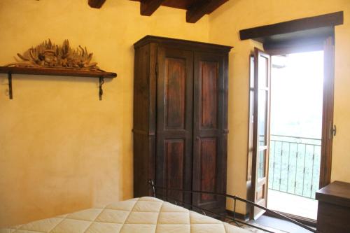 a bedroom with a wooden cabinet next to a window at Bed & Breakfast Triora Medievale in Triora