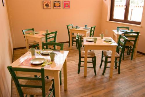 a dining room with wooden tables and green chairs at Sleep'n go Hotel in Fiumicino