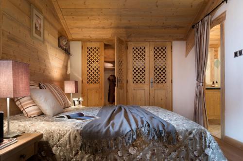 a bedroom with a bed and a wooden wall at CGH Résidences & Spas Les Granges Du Soleil in La Plagne