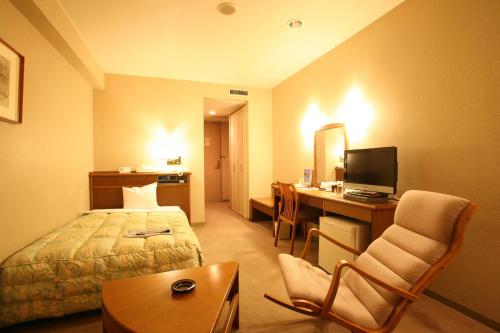 天童市にある天童セントラルホテルのベッドとデスクが備わるホテルルームです。