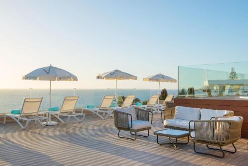 a deck with chairs and umbrellas and the ocean at Iberostar Waves Bouganville Playa in Adeje