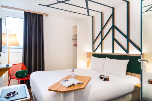 a hotel room with a bed with a table at ibis Styles Rouen Val De Reuil in Val de Reuil