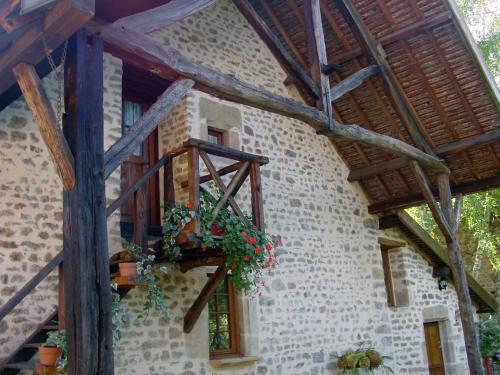 a stone building with a balcony with flowers on it at Chambre d'hotes Ferme de la Forlonge in Sauvigny-le-Beuréal
