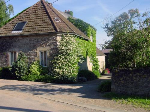 a building covered in ivy next to a street at Chambre d'hotes Ferme de la Forlonge in Sauvigny-le-Beuréal