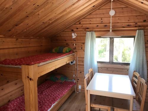 a log cabin with two bunk beds and a table at Svinö Camping Lodge in Lumparland