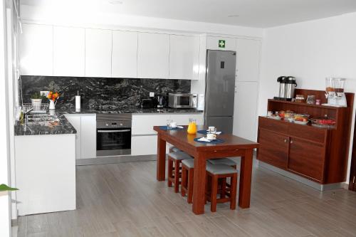 a kitchen with white cabinets and a wooden table at Baleal 4 Surf in Baleal