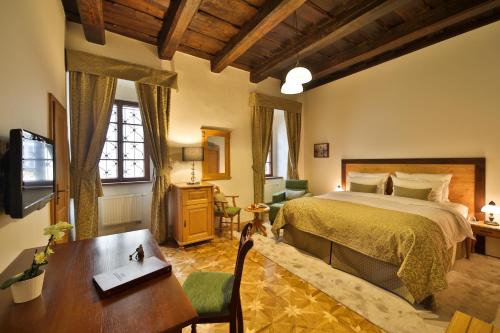 a bedroom with a bed and a desk and a table at Questenberg Hotel in Prague