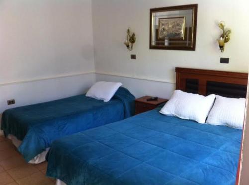 two beds in a room with blue sheets at Hotel Altos de Atacama in Copiapó