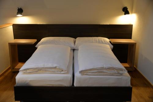 a bed with three pillows on it with two lights at Maison am Liesingbach in Vienna