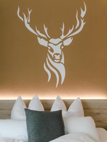 a stenciled deer head on a wall above a bed at Hotel Kitz ehemals Schlemmerhütte in Langweid