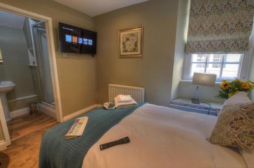 a bedroom with a bed with a remote control on it at Dunster Castle Hotel in Dunster