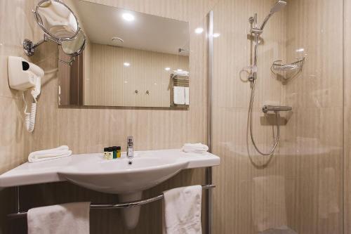 
a bathroom with a shower, sink, and mirror at Hotel Pokrovsky in Pskov

