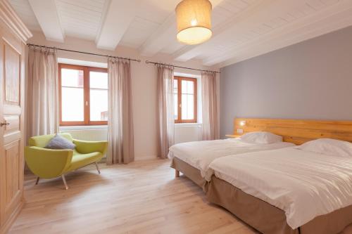 1 dormitorio con 1 cama y 1 silla amarilla en Les Gîtes de la Mère Michèle, en Katzenthal