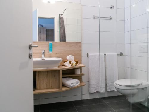 a bathroom with a sink and a toilet and a shower at Schlemmerhütte - Hotel in Langweid