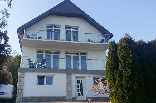 a white house with chairs on the balcony at Lakeview Apartments Balatonfüred in Balatonfüred