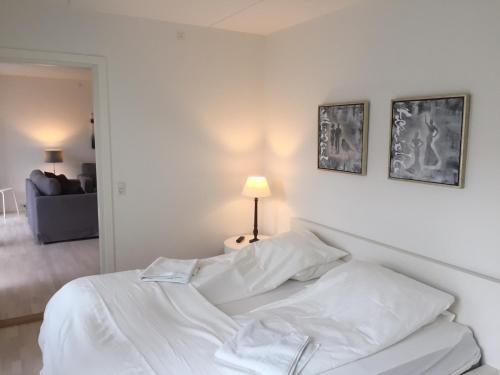 CPH Lux apartm, 2 FULL BATHROOMS 2th في كوبنهاغن: سرير أبيض في غرفة نوم بيضاء مع مصباح