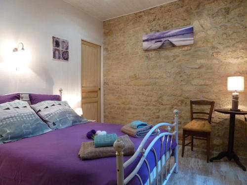 ein Schlafzimmer mit einem lila Bett und einer Steinmauer in der Unterkunft Appartement centre médiéval - Le Cosy de Sarlat in Sarlat-la-Canéda